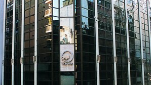 Un bâtiment moderne en verre, doté d’une façade réfléchissante et d’une plaque commémorative au centre.