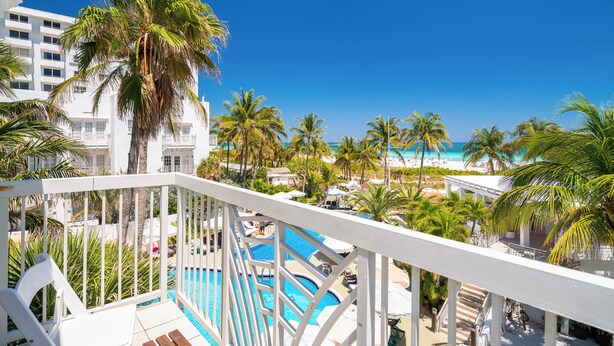 A resort with a pool area, palm trees, and a view of the beach. - The Savoy Hotel & Beach Club (Miami Beach)