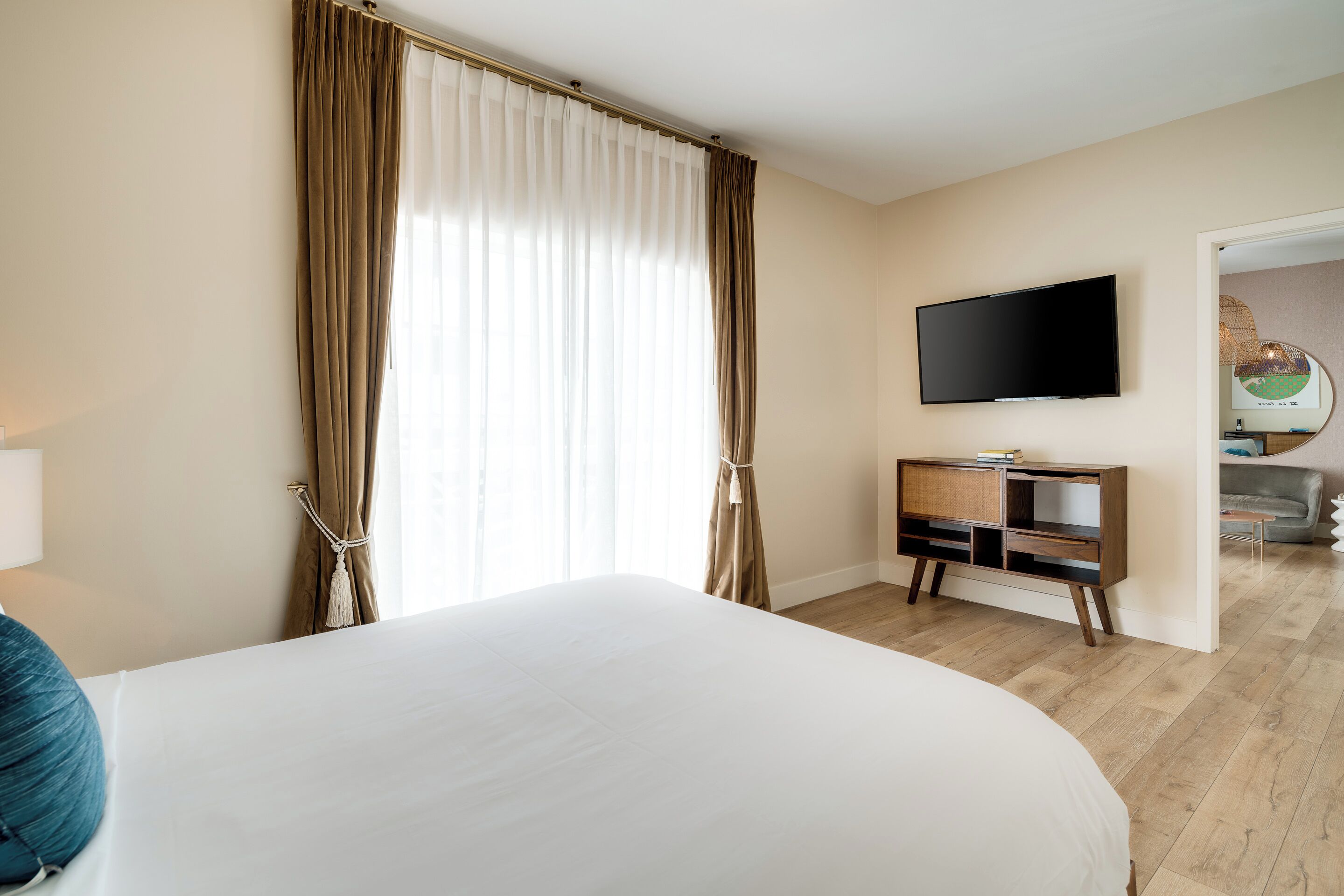 Une chambre d’hôtel avec un grand lit, un téléviseur fixé au mur et une armoire en bois.