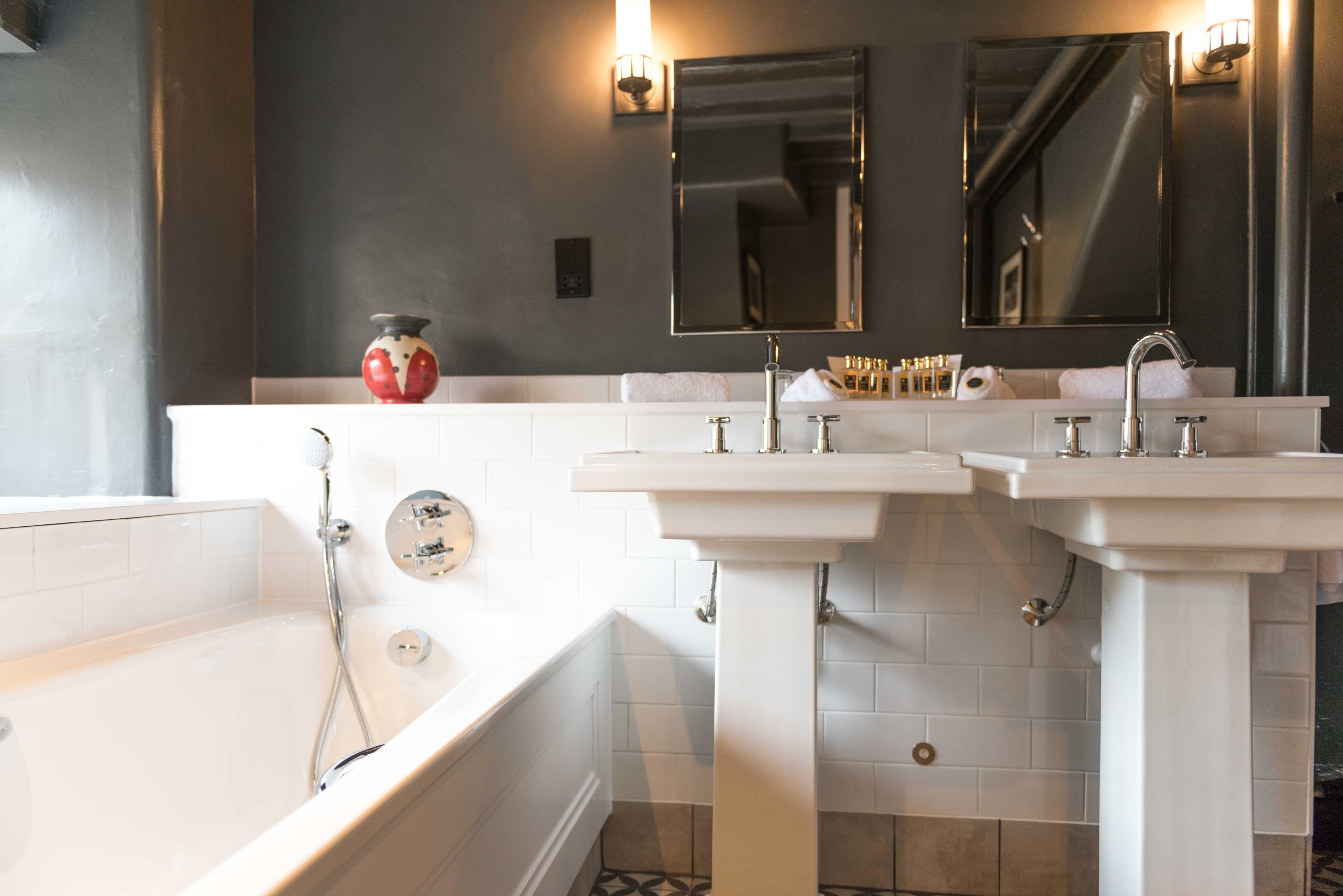 A bathroom with a bathtub, two sinks, and a vanity.