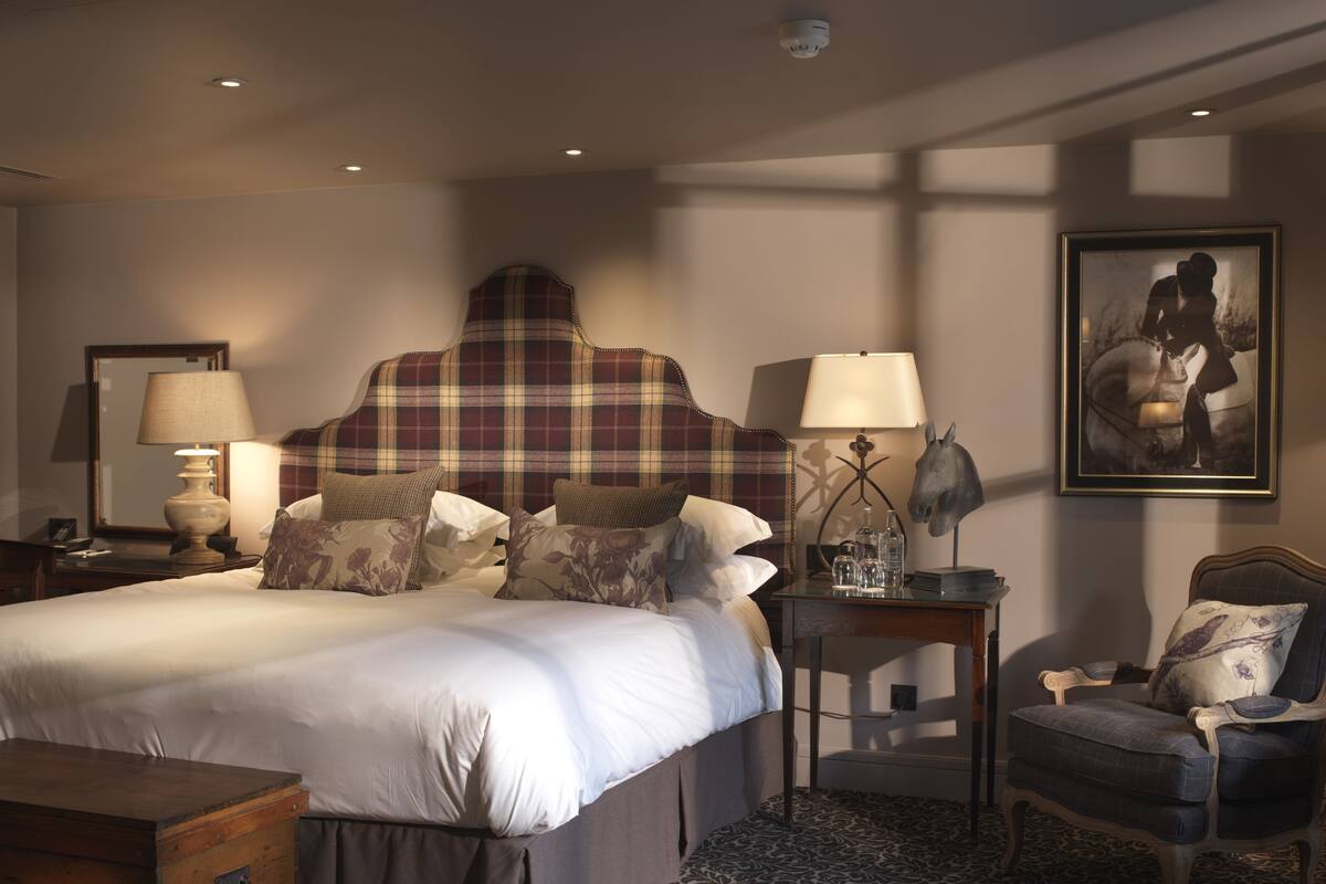 A neatly arranged hotel room with a large bed, bedside tables, a chair, and a dresser.
