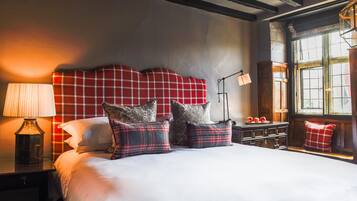 Een net opgemaakt bed met geruite beddengoed, een bedlampje en een nachtkastje met appels.