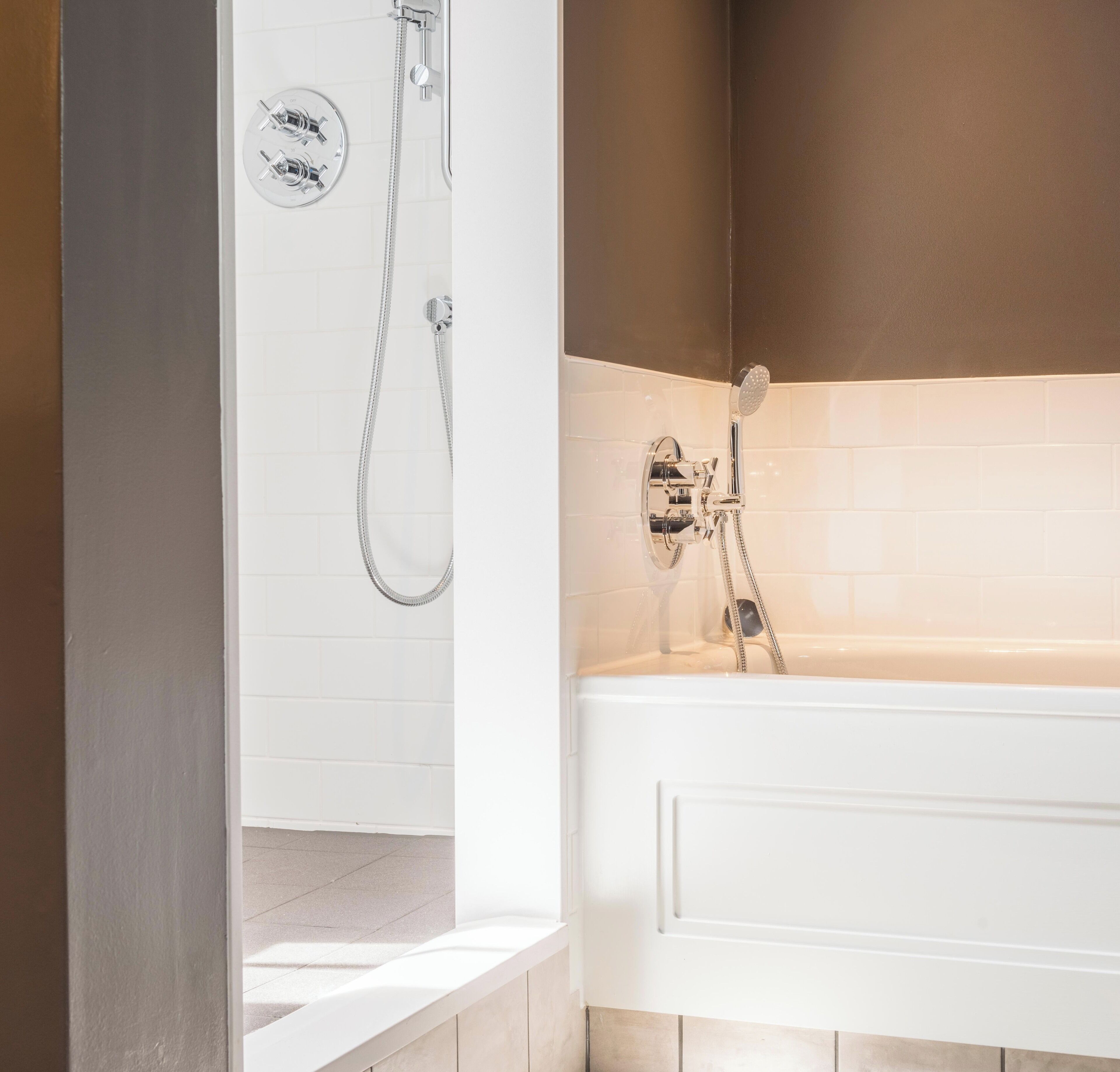A modern bathroom with a bathtub, a shower with a handheld showerhead, and a wall-mounted faucet.