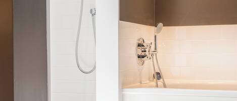 A modern bathroom with a bathtub, a shower with a handheld showerhead, and a wall-mounted faucet.