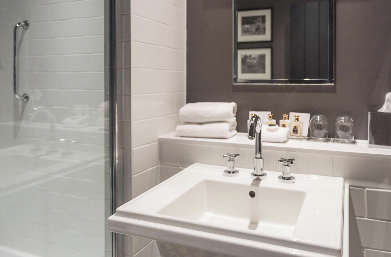 A modern bathroom with a glass shower enclosure, a white sink with chrome fixtures, and a vanity with a mirror above.