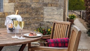 Une table en bois avec deux verres de vin blanc, une bouteille de champagne et une assiette de nourriture.