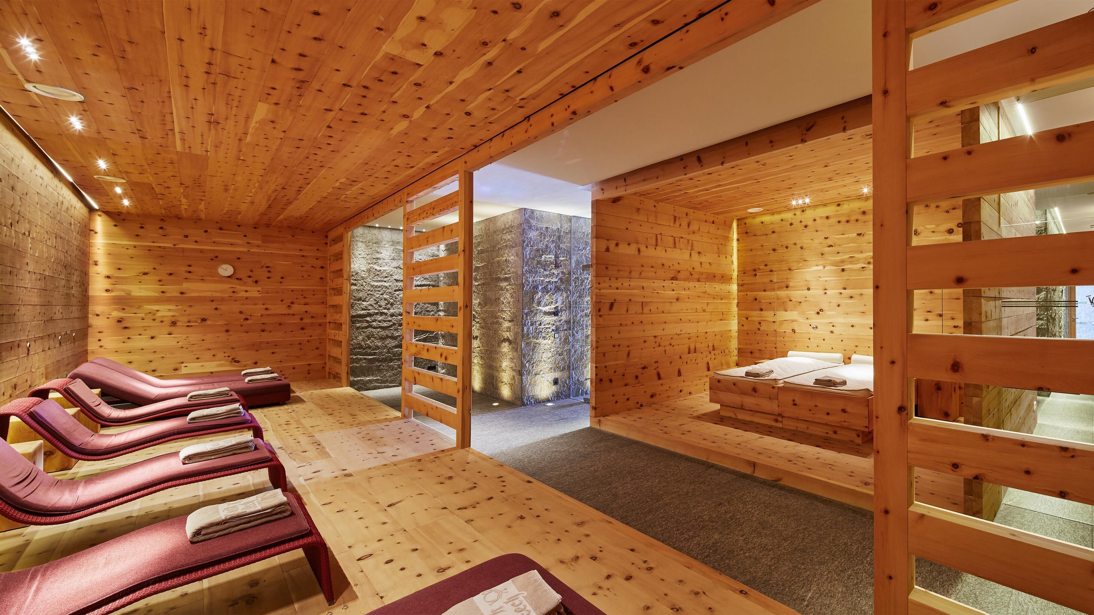 Een houten hut met een sauna, een stenen muur en een bed.