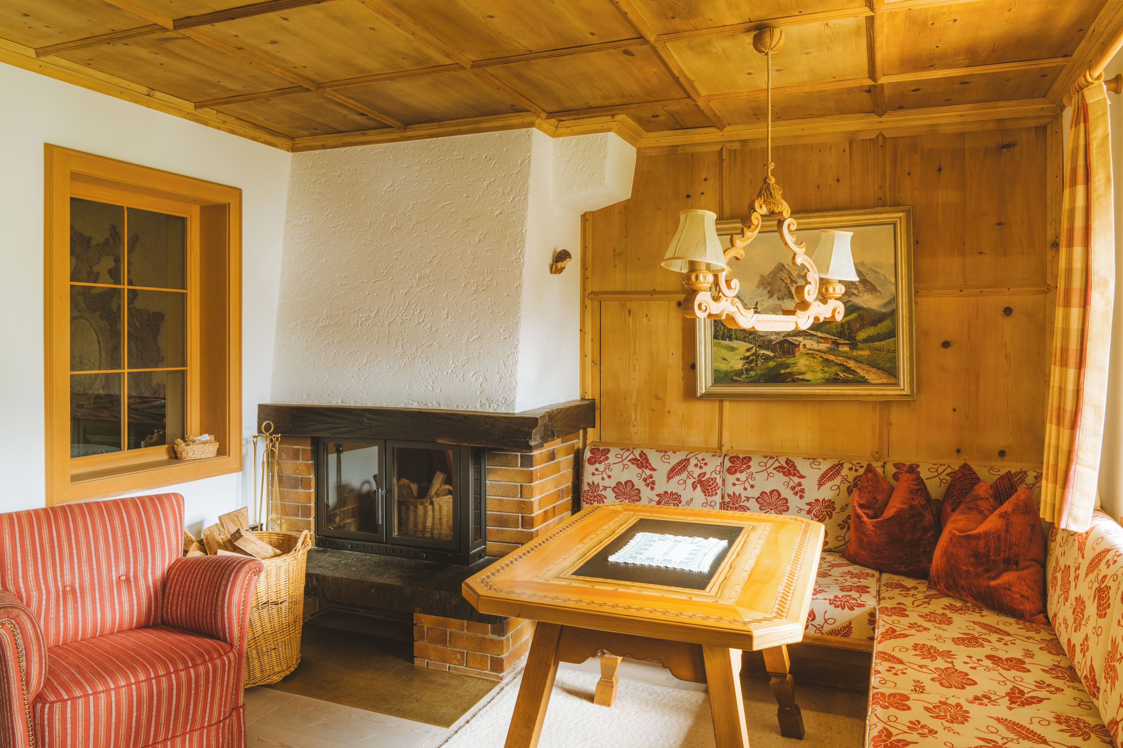 A cozy room with a fireplace, a sofa, a table, and a painting on the wall.