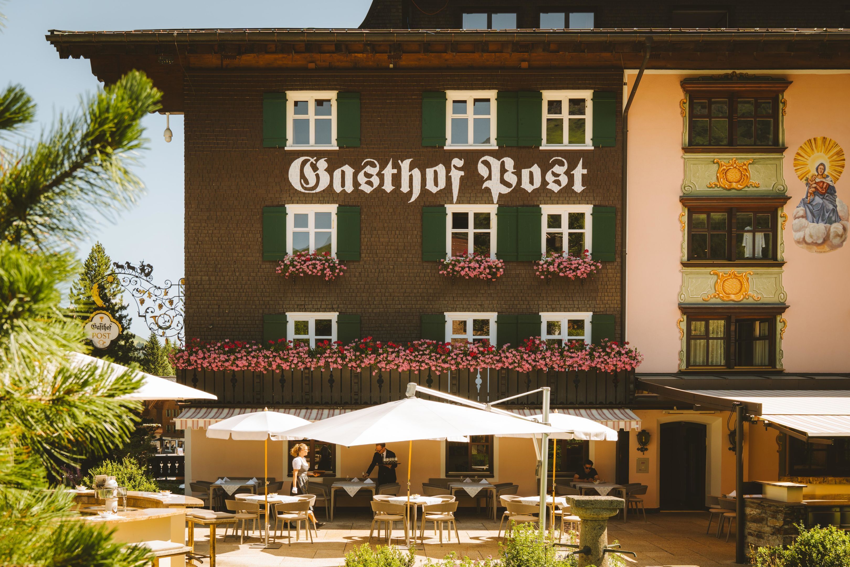 A building with the sign 'Gasthof Post' and outdoor seating with umbrellas.