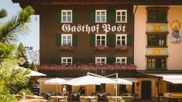 A building with the sign 'Gasthof Post' and outdoor seating with umbrellas.