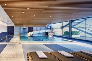 Una piscina cubierta, una piscina al aire libre, tumbonas