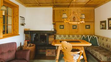 A cozy room with a wooden ceiling, a fireplace, a wooden table, a bench, and a chair.