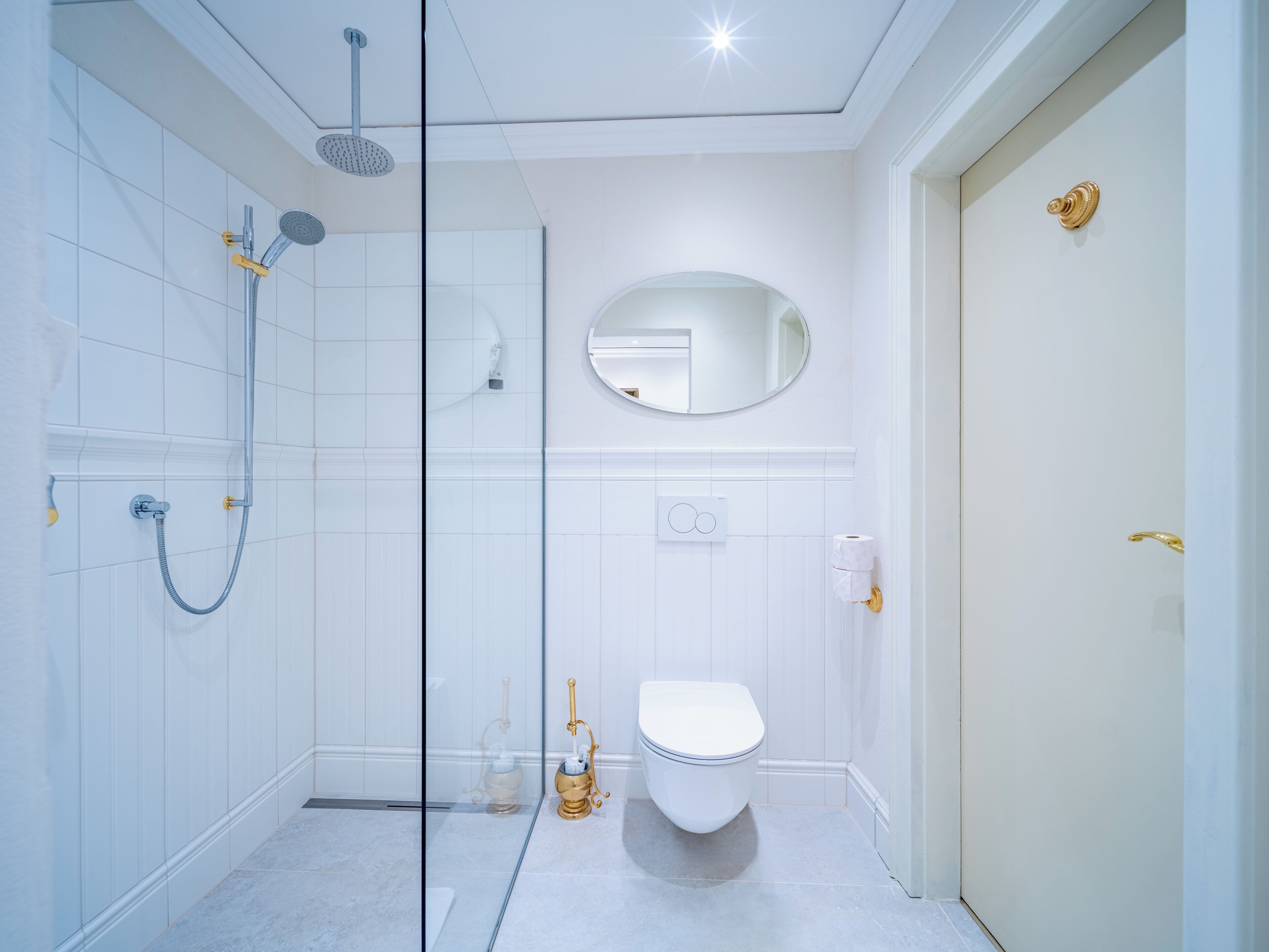 A modern bathroom with a glass shower enclosure, a toilet, a bidet, and a mirror.