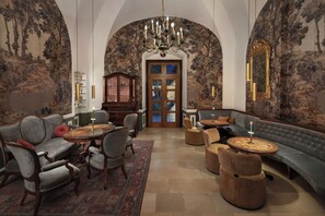 A spacious room with a high arched ceiling, a grand chandelier, a traditional wooden cabinet, and a large mirror. - Hotel Schloss Durnstein (Durnstein)