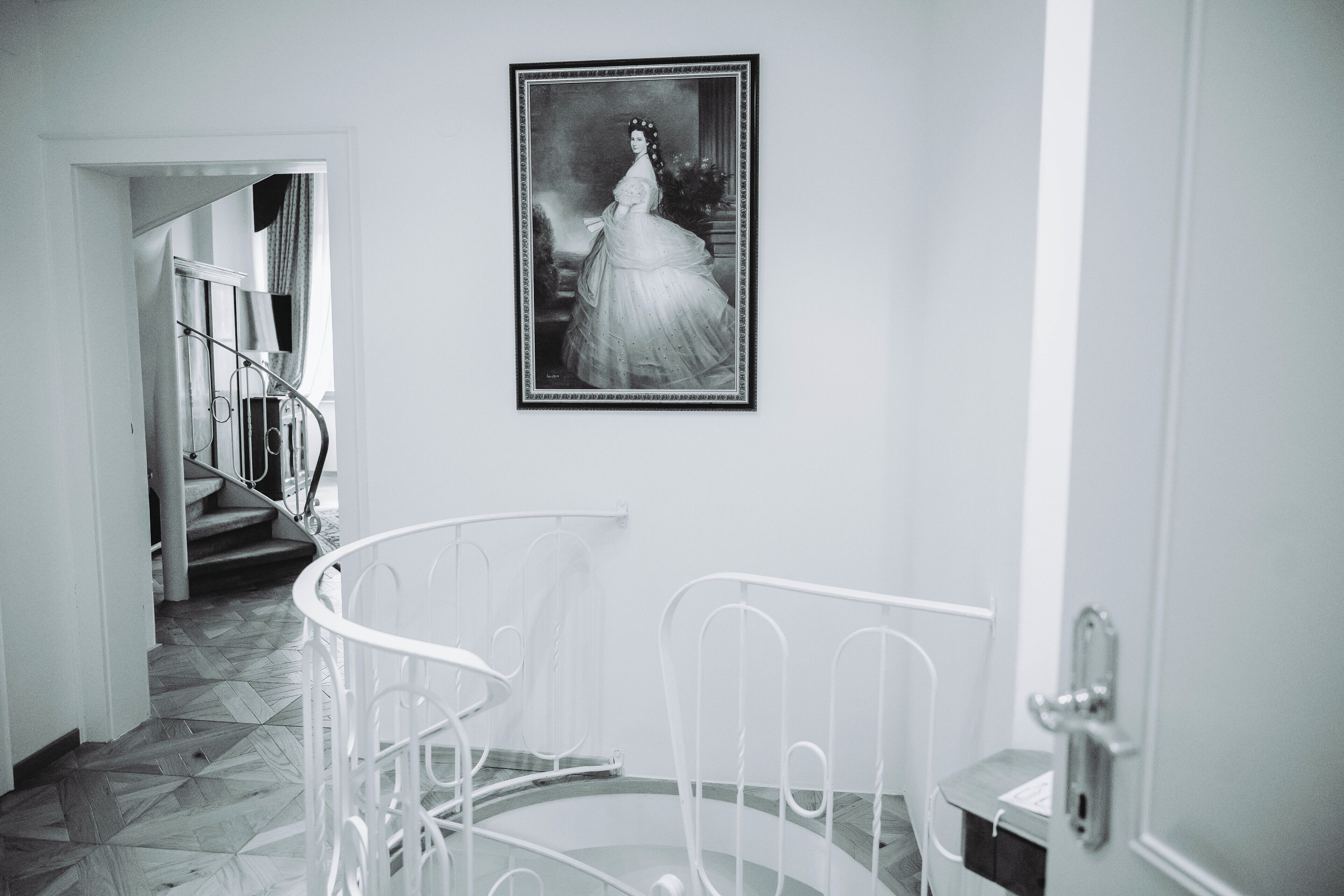 Eine Treppe mit Metallgeländer, ein gerahmtes Schwarz-Weiß-Foto an der Wand und eine Tür mit Griff.