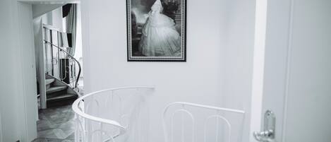 A staircase with a metal railing, a framed black and white photograph on the wall, and a door with a handle.