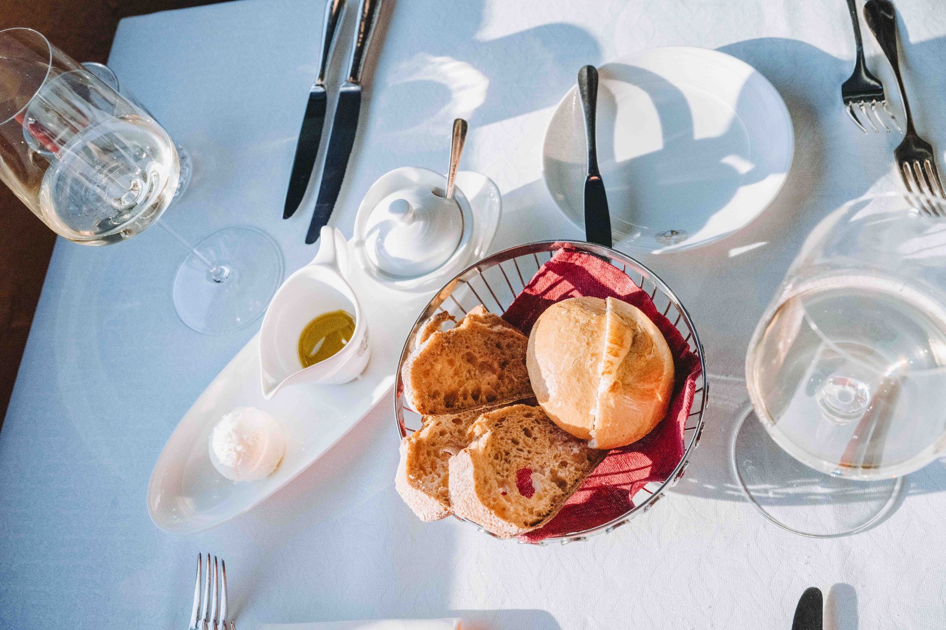 A table set with bread, a small bowl of sauce, and a glass of water.