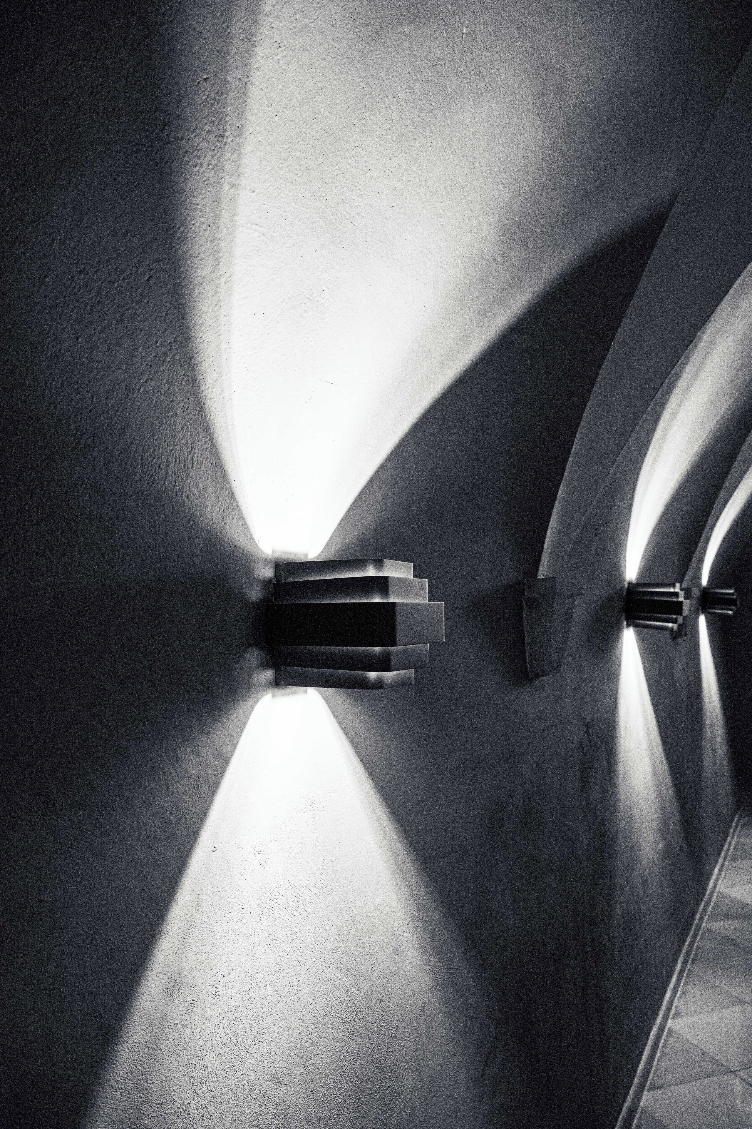A corridor with a modern light fixture casting shadows on the walls.