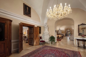 A spacious lobby with a grand chandelier, wooden doors, and a large rug. - Hotel Schloss Durnstein (Durnstein)