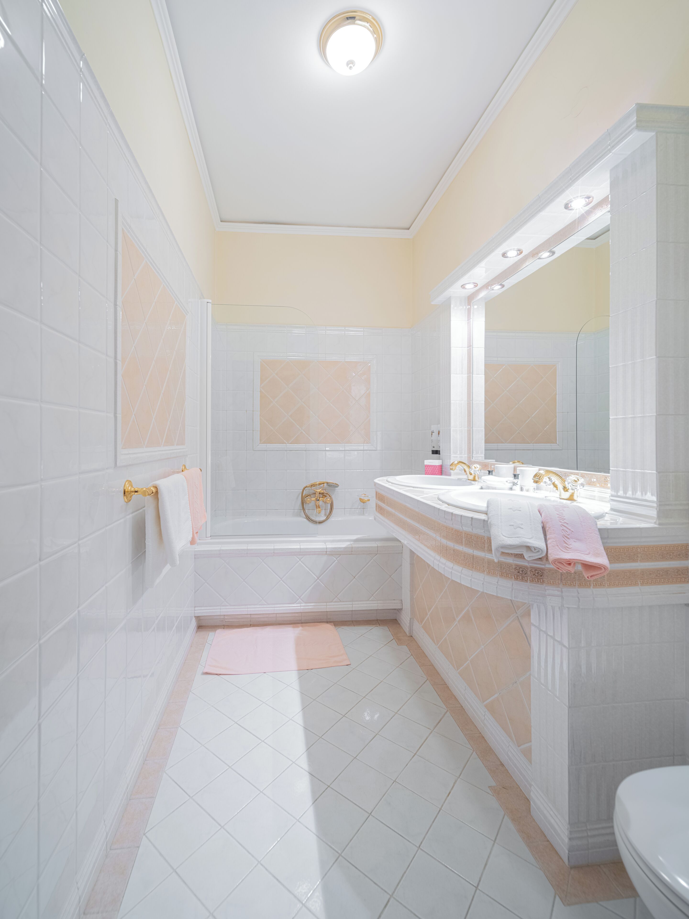 Un baño con azulejos blancos, una bañera, un tocador con espejo y un inodoro.