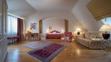 Amplio dormitorio tipo loft con una cama grande, una zona de estar con sofá y sillones, un escritorio con silla y una mesa de comedor.