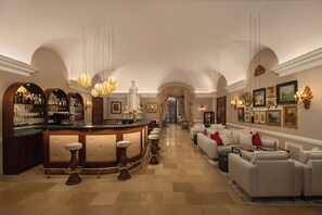 A bar area with stools, a counter with bottles, and a seating area with sofas and a coffee table. - Hotel Schloss Durnstein (Durnstein)