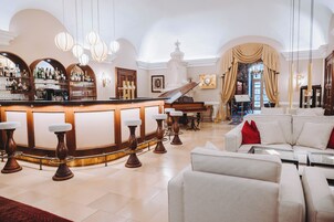 A bar area with stools, a piano, and a seating area with a sofa and armchairs.