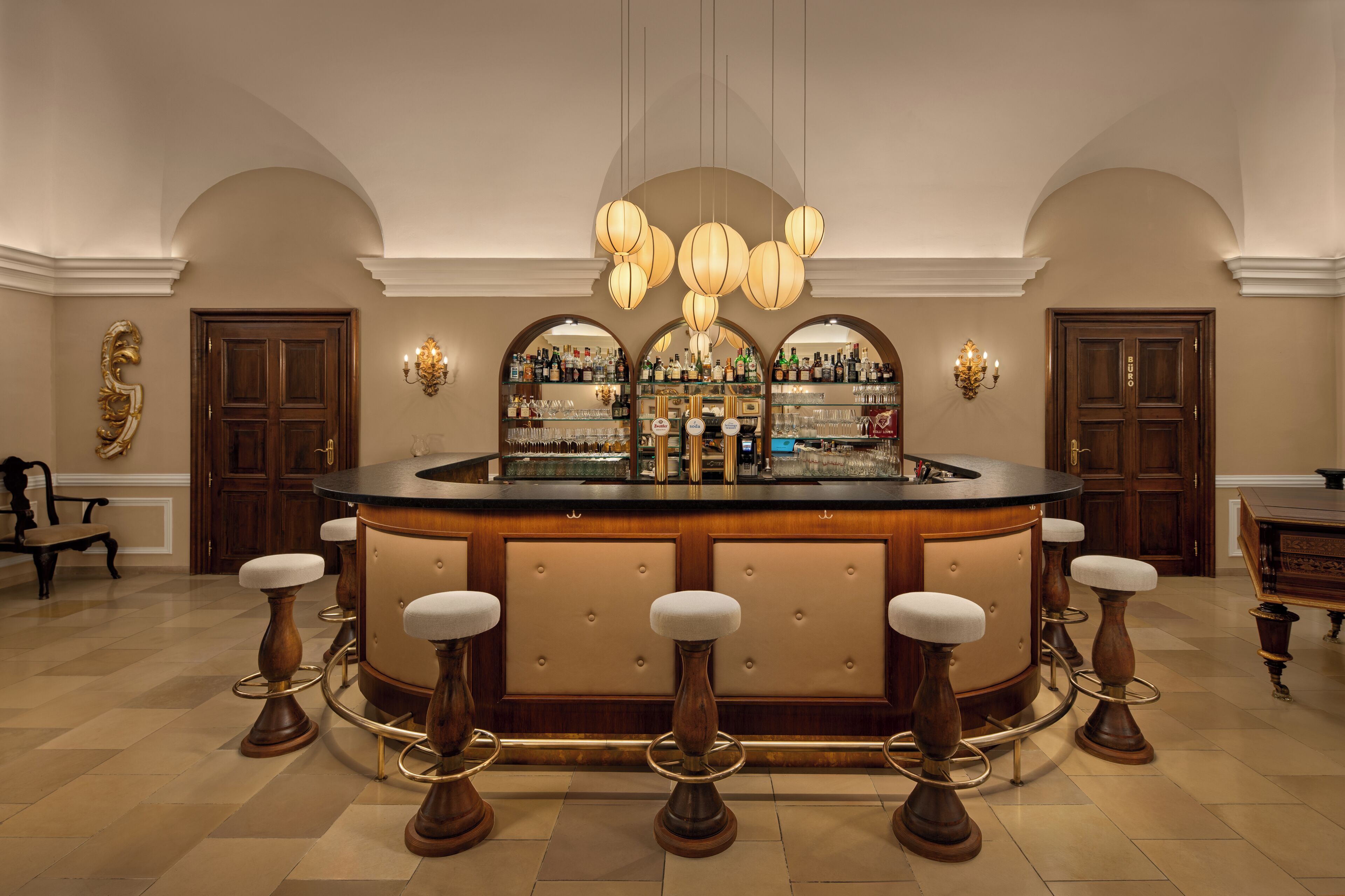 A bar area with a round counter, stools, and a wine rack with bottles.