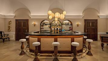 A bar area with a round counter, stools, and a wine rack with bottles.