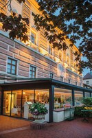 A historic building with a brick facade, large windows, and a covered outdoor seating area with tables and chairs.