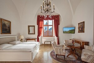 A hotel room with a bed, a round table, a chair, a TV, and a window with curtains.