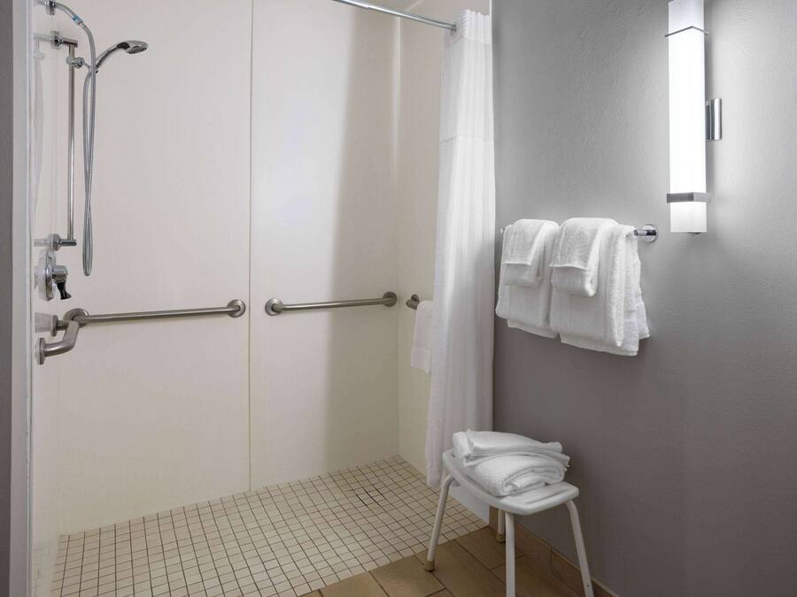 A bathroom with a shower, a towel rack, and a small stool.