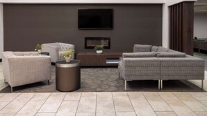 A modern living room with a sofa set, a coffee table, and a flat-screen TV mounted on the wall.