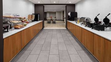 Un área de cocina moderna con mesas de buffet, diversas estaciones de comida y una máquina de café.