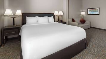 A hotel room with a large bed, two bedside tables with lamps, a small sofa, and a framed picture on the wall.
