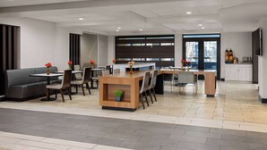A modern hotel lobby with a reception desk, seating area, and a large window.