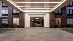 A modern building entrance with a glass door, a flat roof, and a concrete ground.