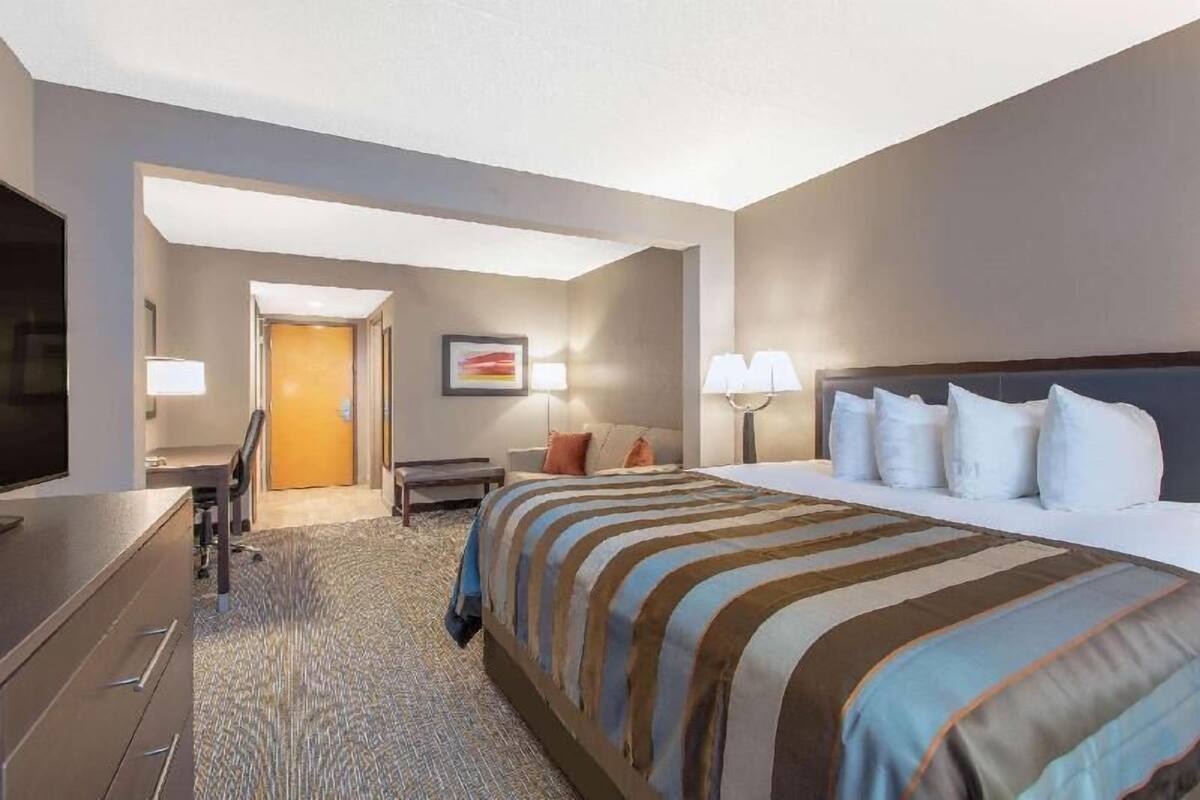 A hotel room with a bed, desk, chair, and television.