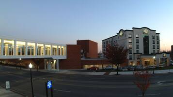 A hotel with a modern design, featuring a prominent sign and a parking lot with several cars.