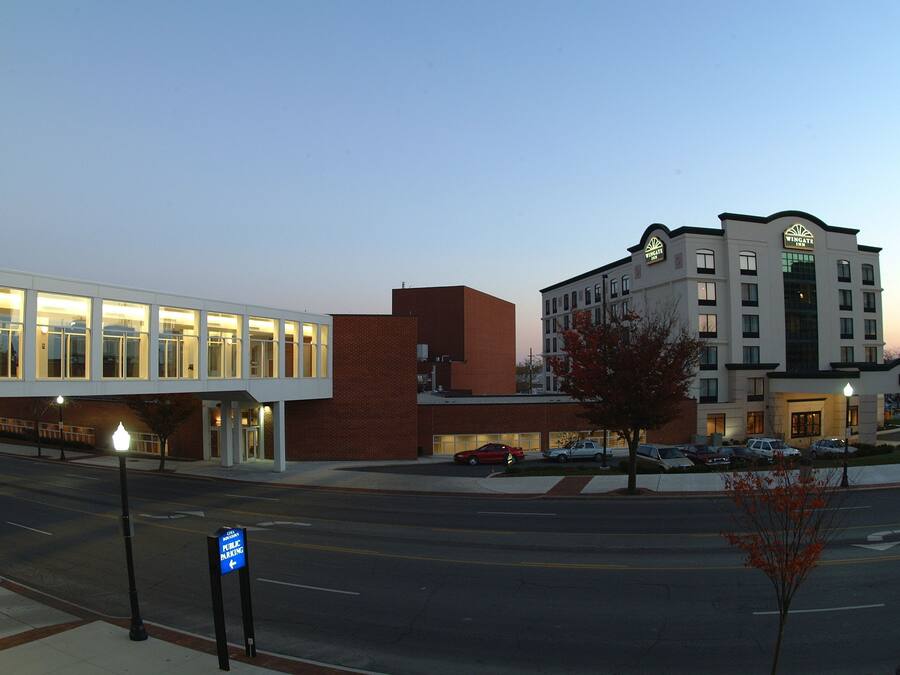 A hotel with a modern design, featuring a prominent sign and a parking lot with several cars.
