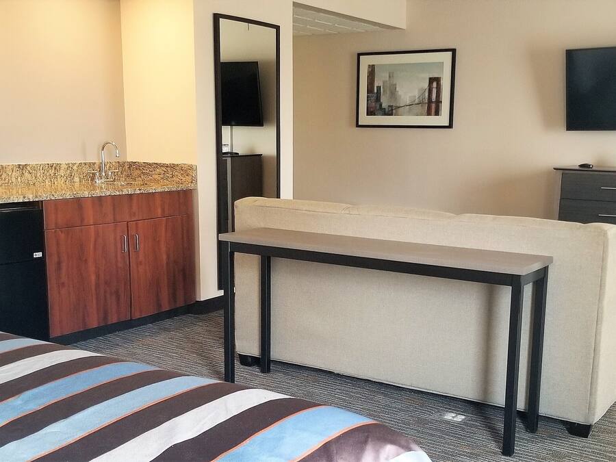 A hotel room with a bed, a small kitchenette with a microwave, a coffee maker, and a TV.