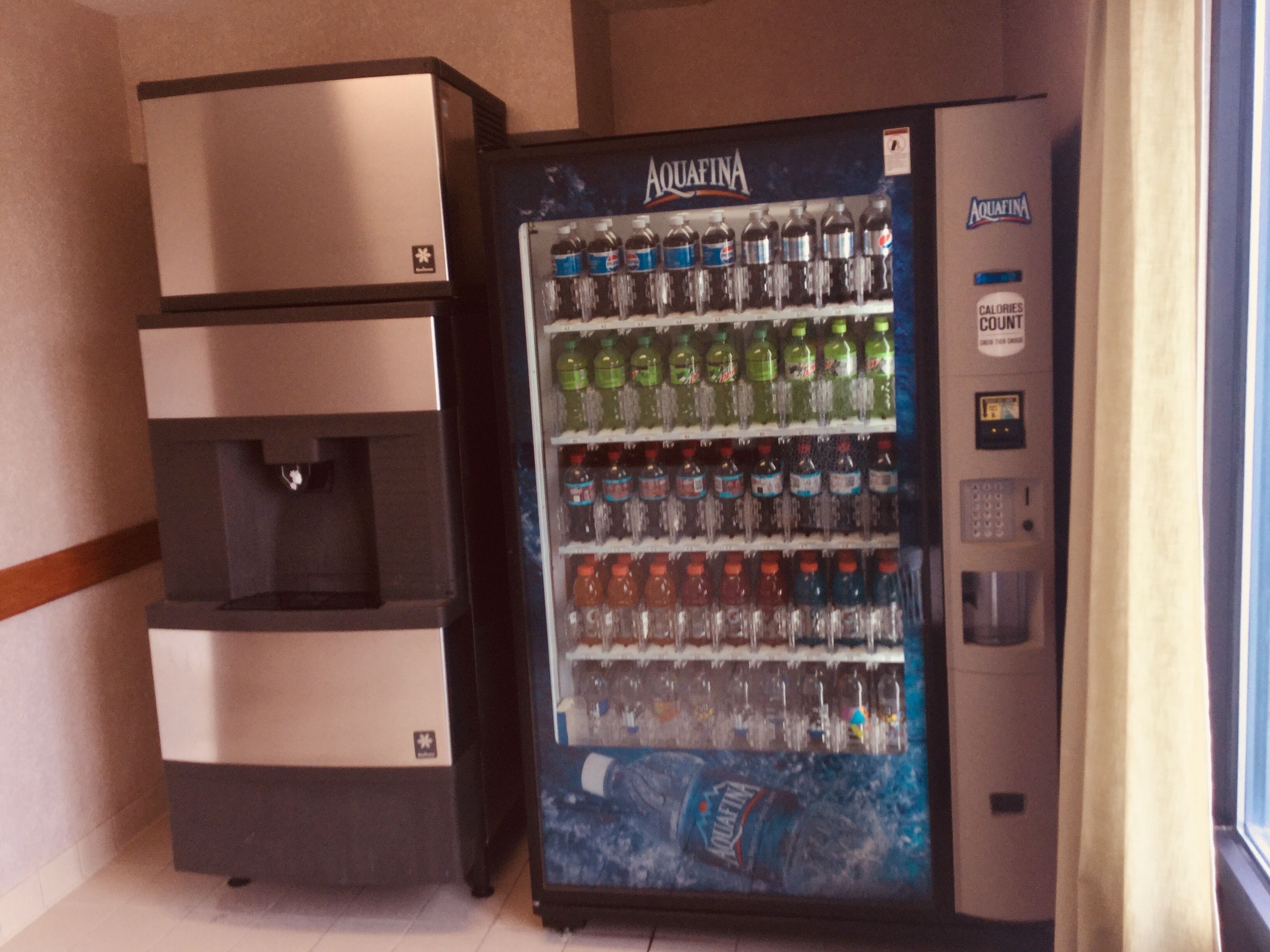 A vending machine with multiple beverage options, including Aquafina water, and a small refrigerator with a water dispenser.