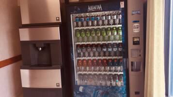 A vending machine with multiple beverage options, including Aquafina water, and a small refrigerator with a water dispenser.
