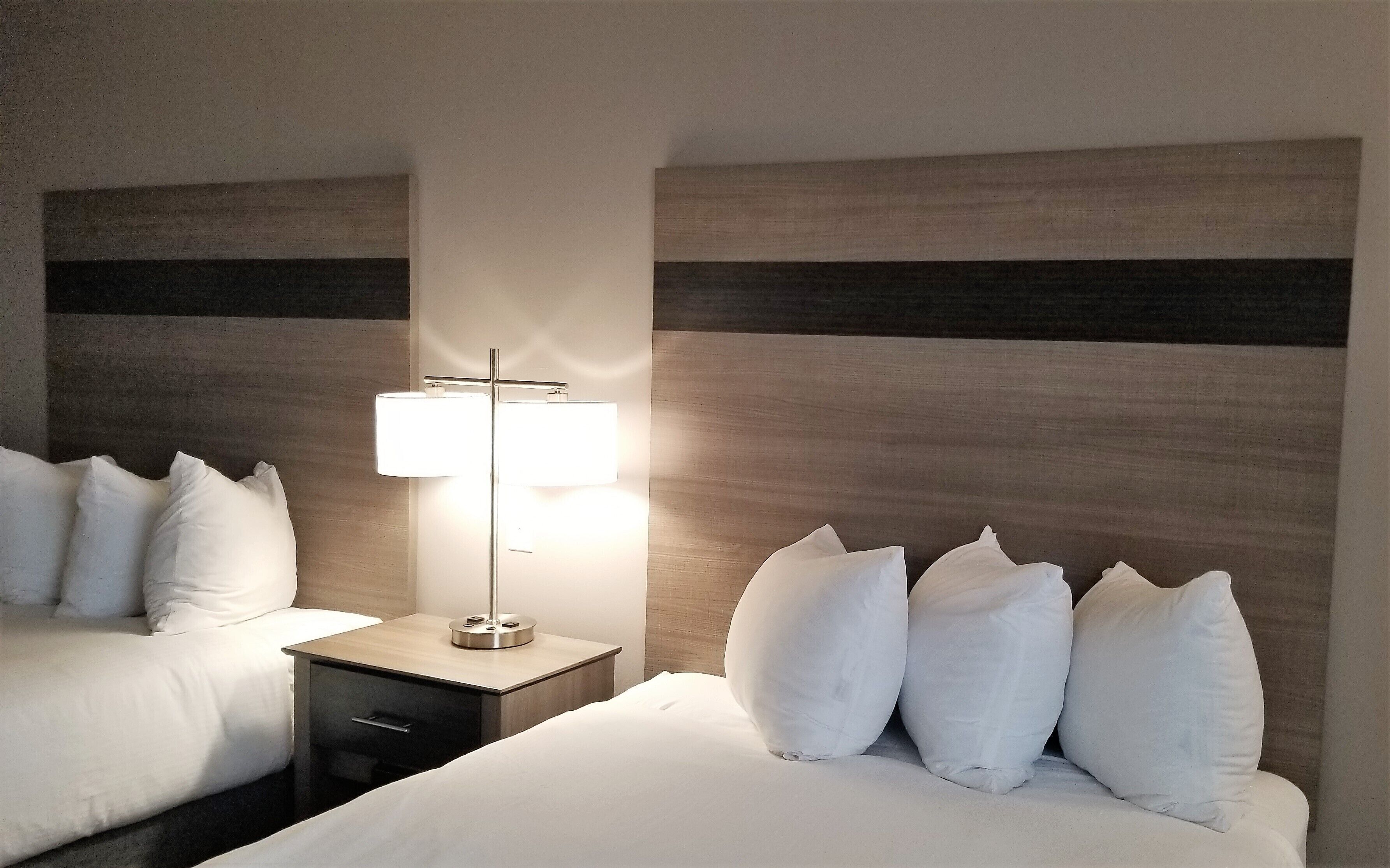 Ein Hotelzimmer mit zwei Betten, einem Nachttisch und einer Lampe.