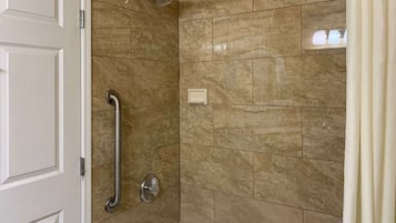 A bathroom with a shower, grab bars, and a bathtub.