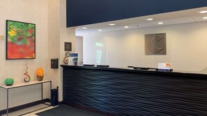 A reception desk with a modern design, a framed artwork on the wall, and a small table with decorative items. - Comfort Inn Saint Paul East (Oakdale)