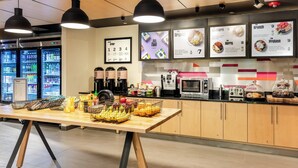 A modern kitchen area with a wooden counter, black pendant lights, and a menu board displaying various food options. - Aloft by Marriott Columbia Harbison (Columbia)