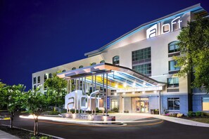 A modern hotel with a prominent 'aloft' sign, a covered entrance, and a landscaped area with trees. - Aloft by Marriott Columbia Harbison (Columbia)