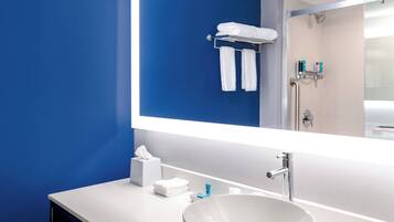 A modern bathroom with a large mirror, white sink, and blue walls.