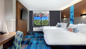 A modern hotel room with a large bed, a desk with a chair, a flat-screen TV, and a window with a view of trees. - Aloft by Marriott Columbia Harbison (Columbia)